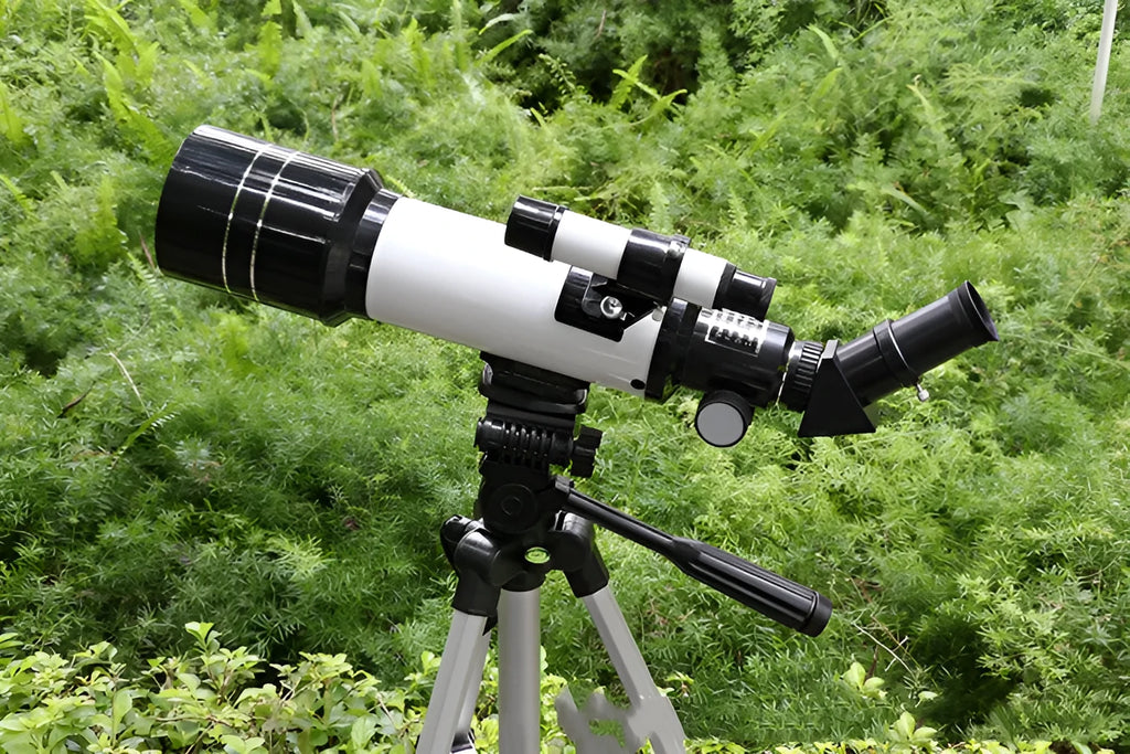 Dark blue and white children's astronomical monocular telescope on a tripod with a mobile phone holder attached.