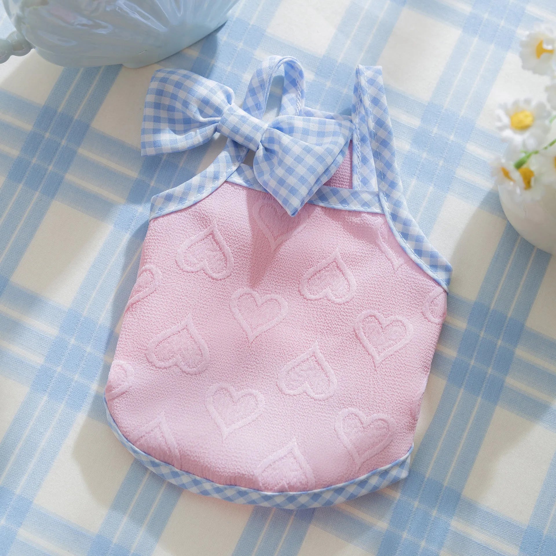 Small dog wearing a blue elastic vest with a heart texture and bow suspenders.