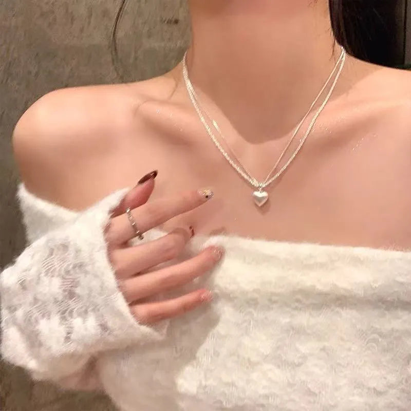 Brushed double-layer heart pendant necklace with adjustable chain on white background