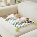 Plush pet blanket with plaid pattern and fur ball decoration for cats and dogs on sofa