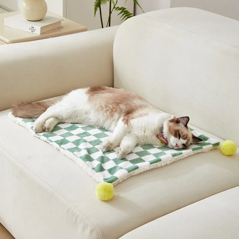 Plush pet blanket with plaid pattern and fur ball decoration for cats and dogs on sofa