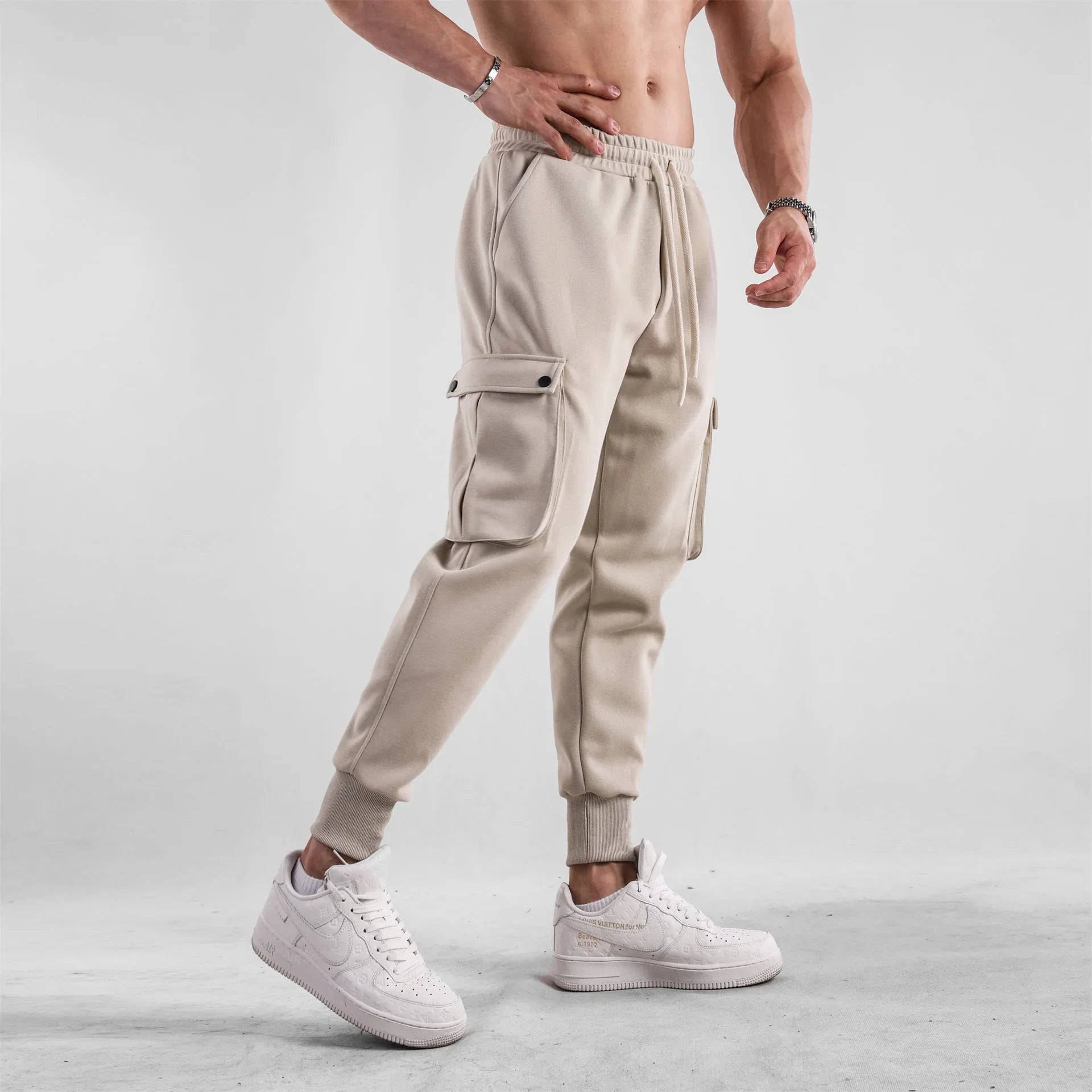 Men's loose-fit cotton sports trousers in apricot colour with ankle ties and multiple pockets, laid flat.