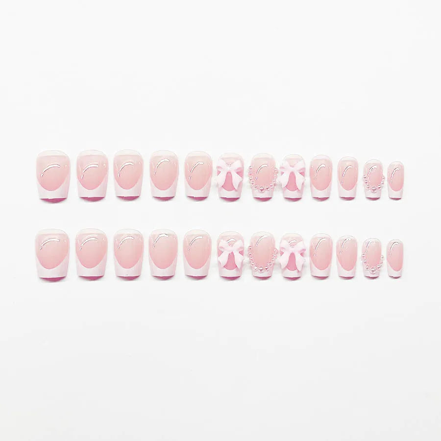 Set of 24 white French manicure false nails with bow and tulip designs, next to bottles of S274 glue and jelly glue.