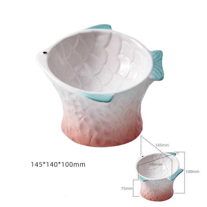 Blue ceramic fish-shaped cat bowl with tilted design and non-slip base on a wooden surface