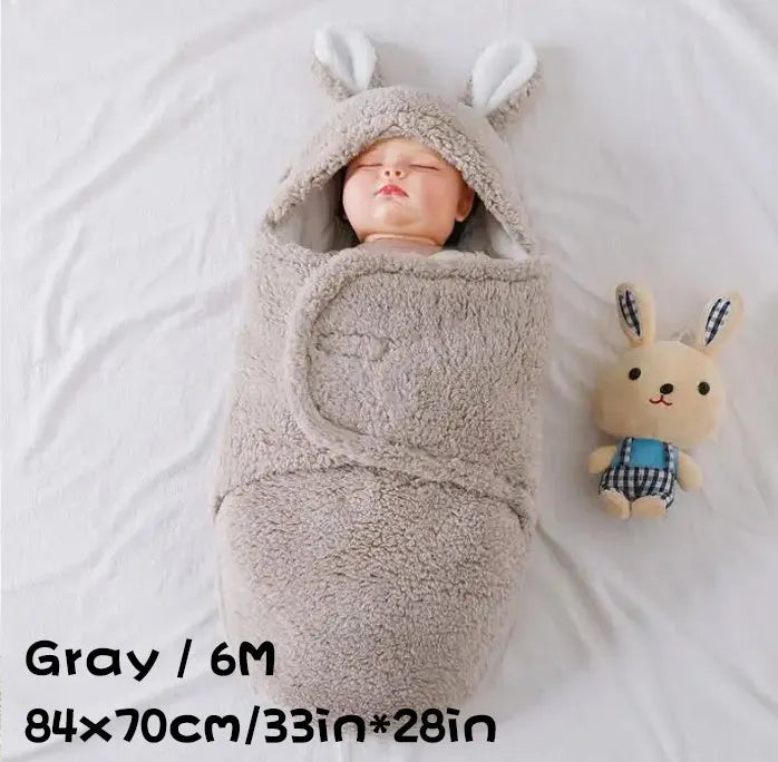 Baby wearing a grey adjustable fleece swaddle sleep sack with velcro wings