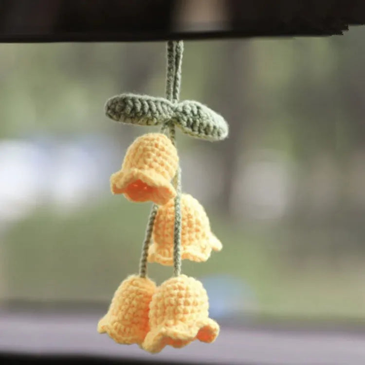Green and white knitted wool car plant ornament hanging from a rope