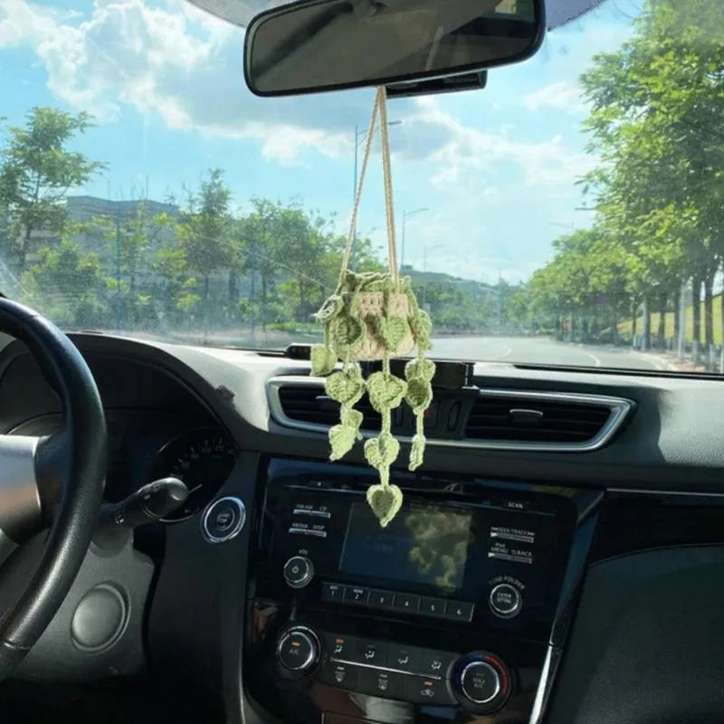 Green and white knitted wool car plant ornament hanging from a rope