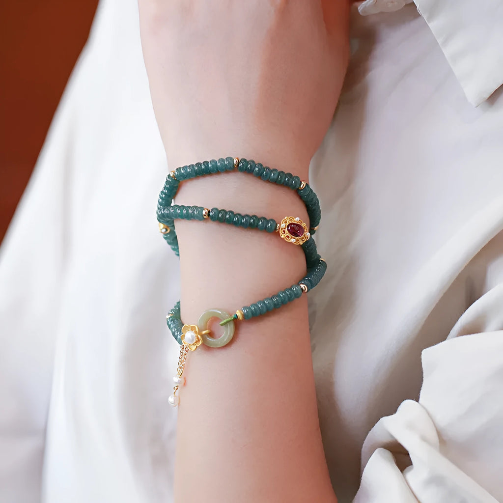 Women's bracelet with small blue water jade abacus beads, tourmaline rings, and pearls on a wrist