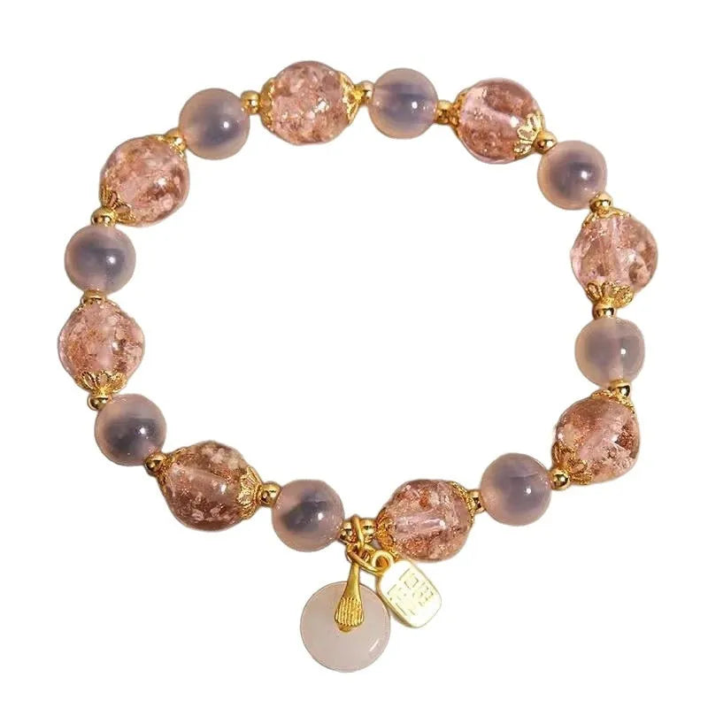 Close-up of a women's pink agate heart bracelet with a luminous glaze and a silver peace buckle clasp.