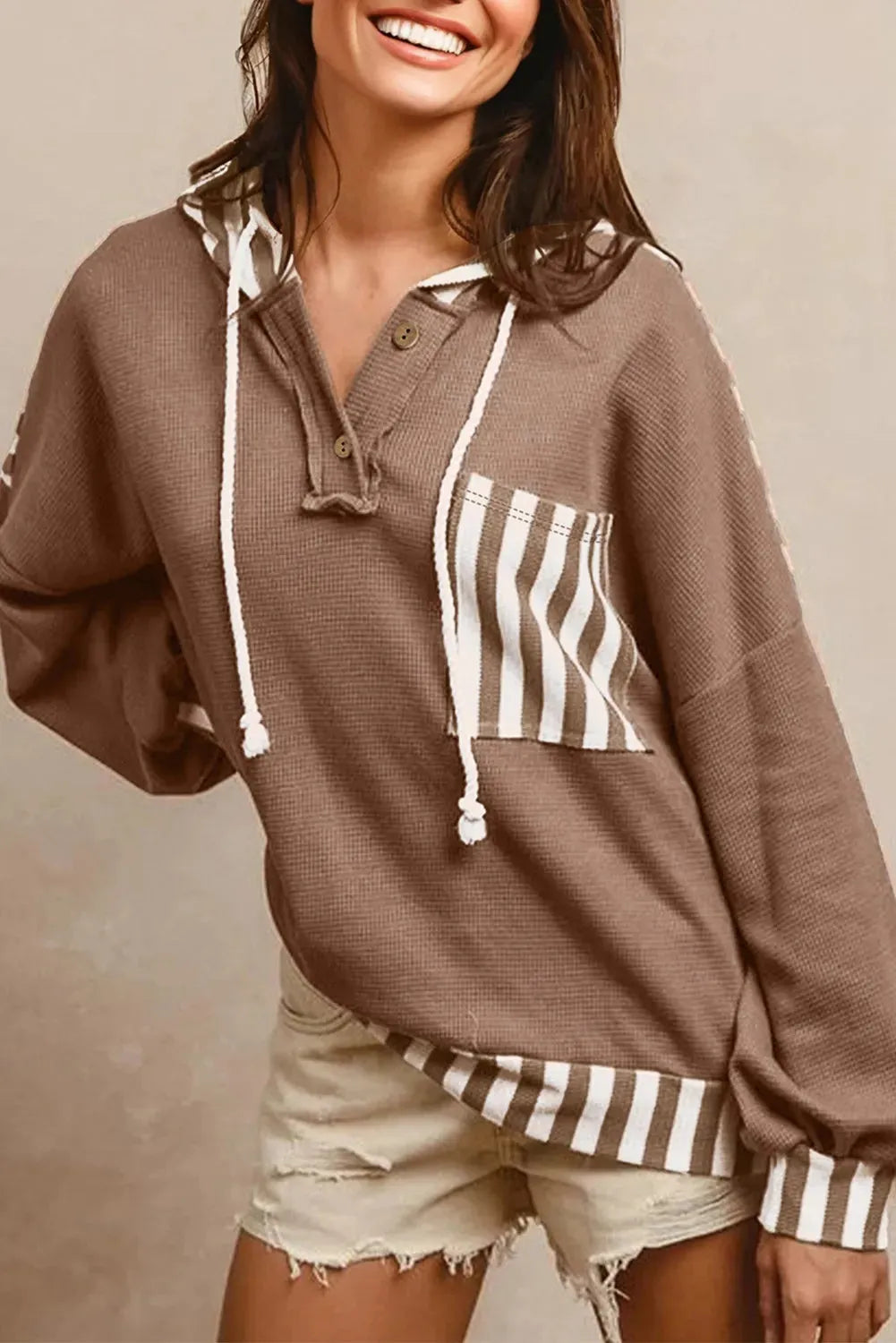 Straw yellow striped hoodie with waffle texture patchwork, button neck, and drawstring hood laid flat.