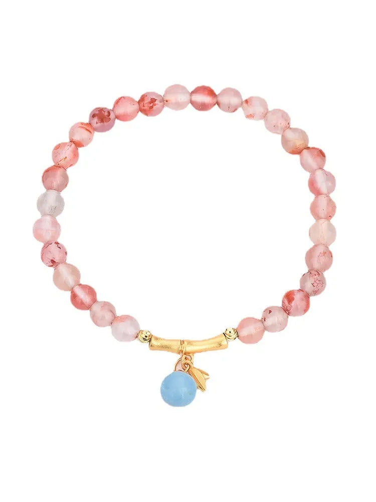 Polished Nanhong Agate flower bracelet with bamboo joint design on wrist.