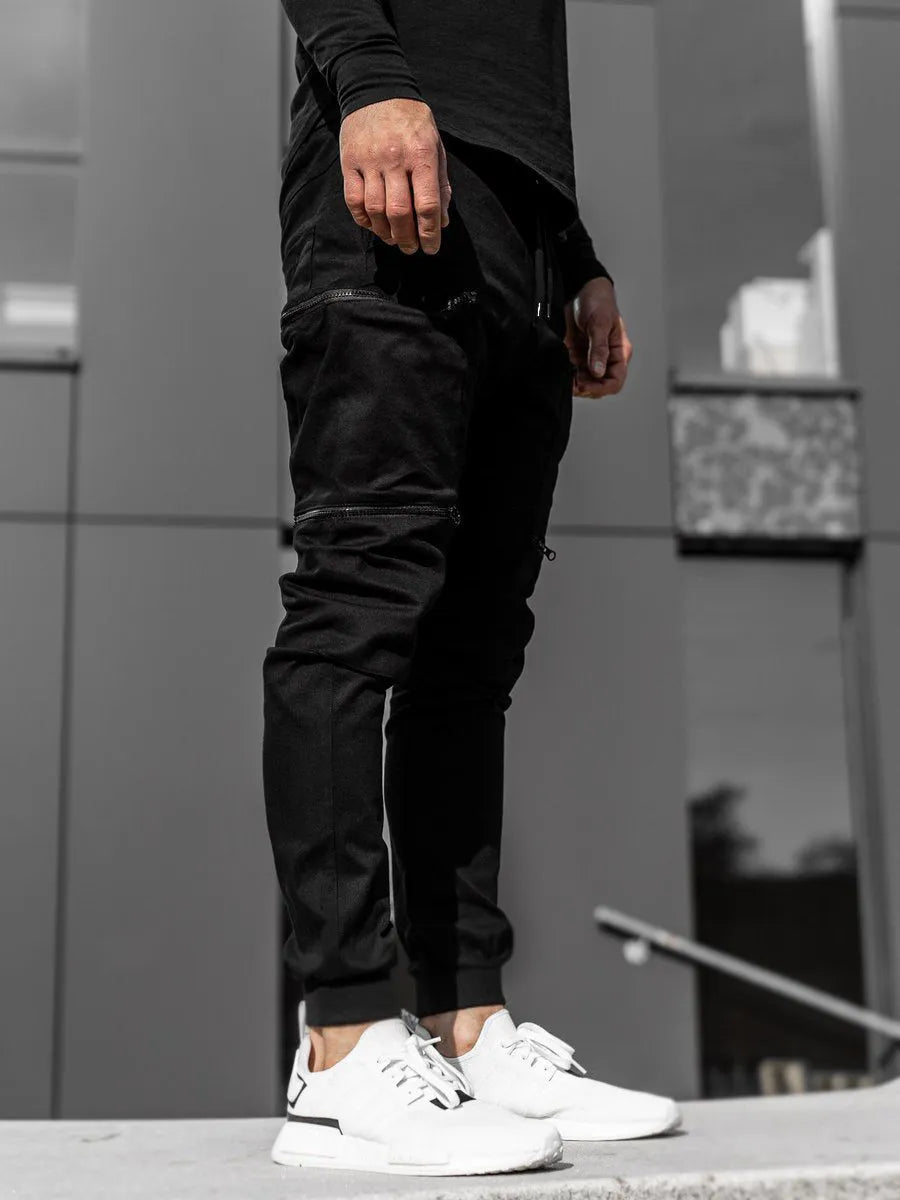 Men's tight fit multi-pocket cotton trousers in black, shown with multiple front pockets and tethered details on waistband.