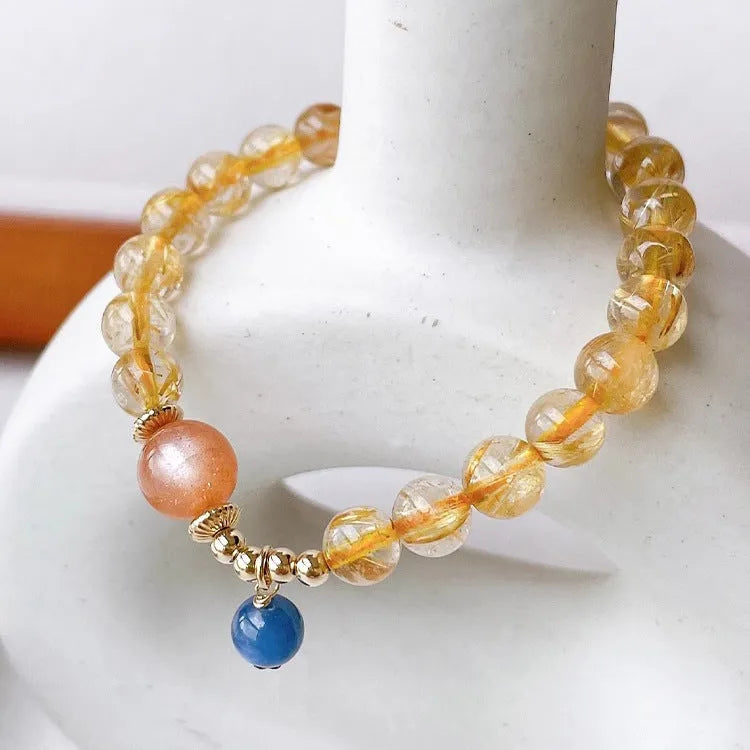 Gold rutilated quartz sunstone crystal bracelet with diamond-cut beads on wrist