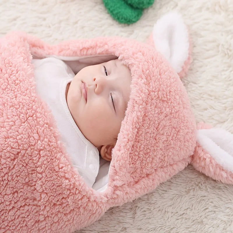 Baby wearing a grey adjustable fleece swaddle sleep sack with velcro wings