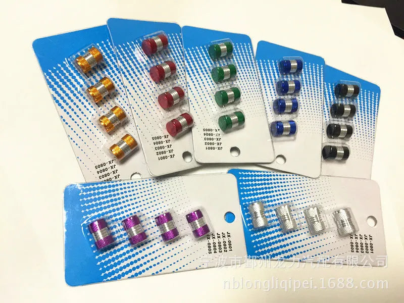 Seven aluminium alloy tyre valve dust caps in black, blue, gold, green, purple, red, and silver on a white background