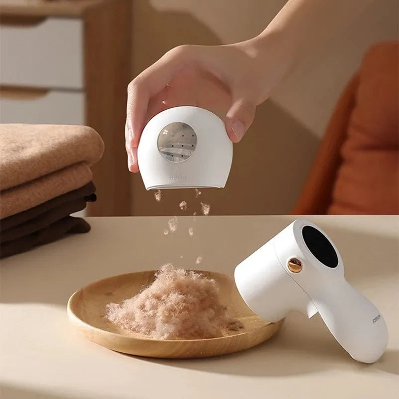 White electric lint remover with LED display and USB charging port on a fabric surface.