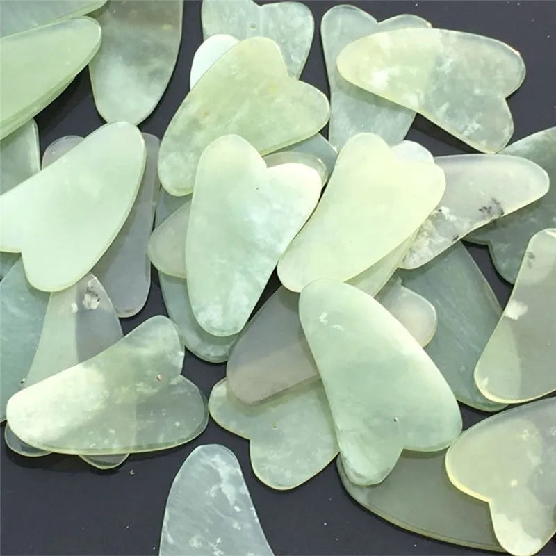 Flat natural jade gua sha stone for facial massage in green colour on white background