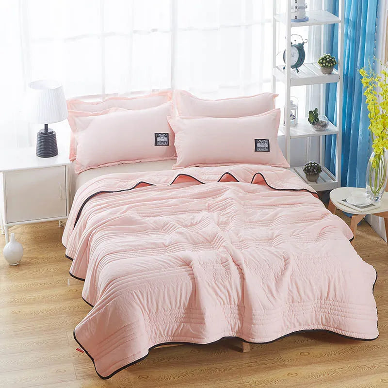 Lightweight seersucker summer quilt in various colours on a bed
