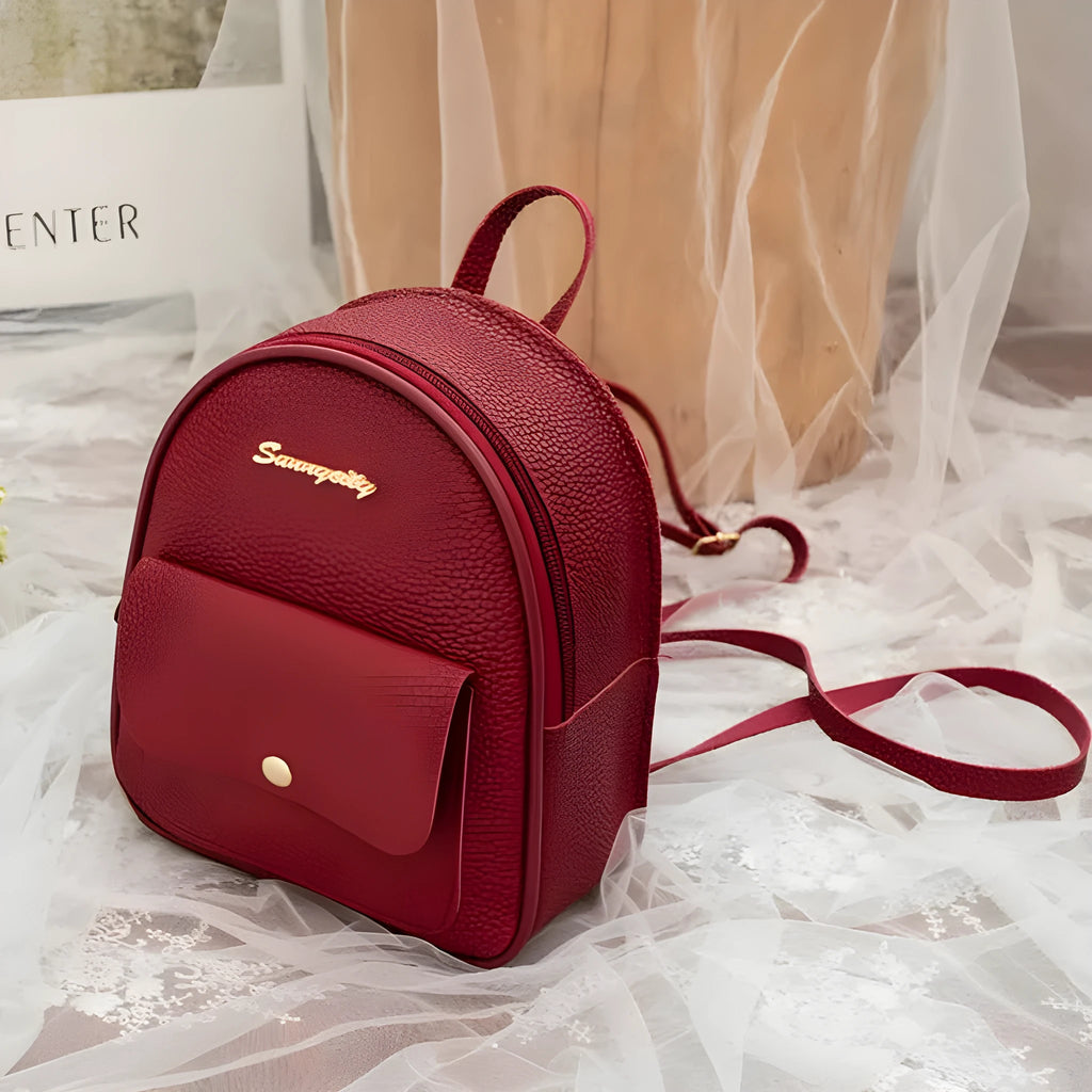 Compact black PU leather women's shoulder backpack worn crossbody, showing zipper closure and simple design.