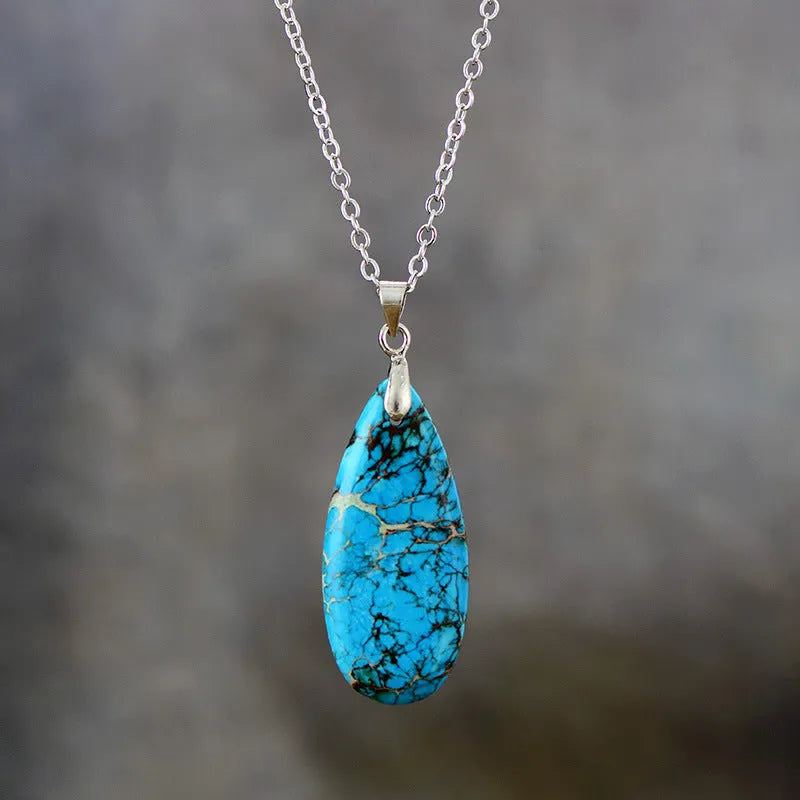 Close-up of an Emperor Stone necklace with a teardrop-shaped green jade pendant on a gold-plated chain, showing natural stone veining.