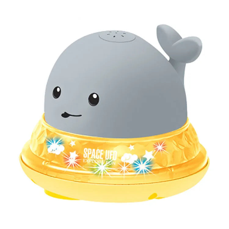 Grey and white cartoon whale bath toy spraying water with LED lights illuminated on water surface.