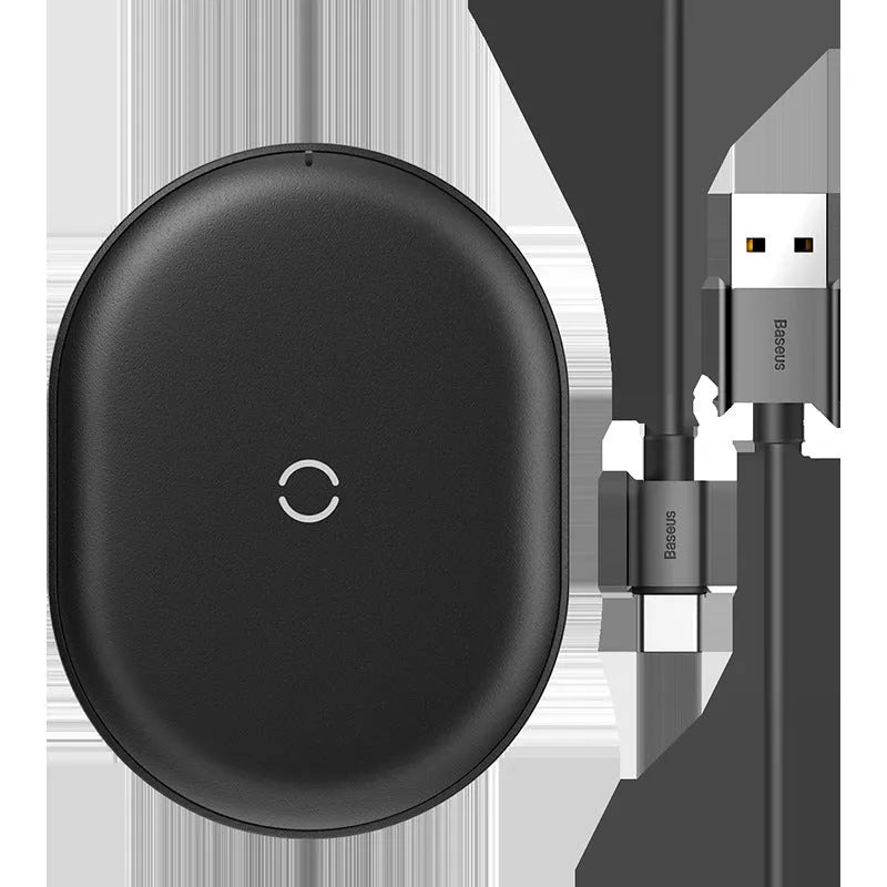 Baseus Rough 15W wireless charging pad in black on a table next to a mobile phone.