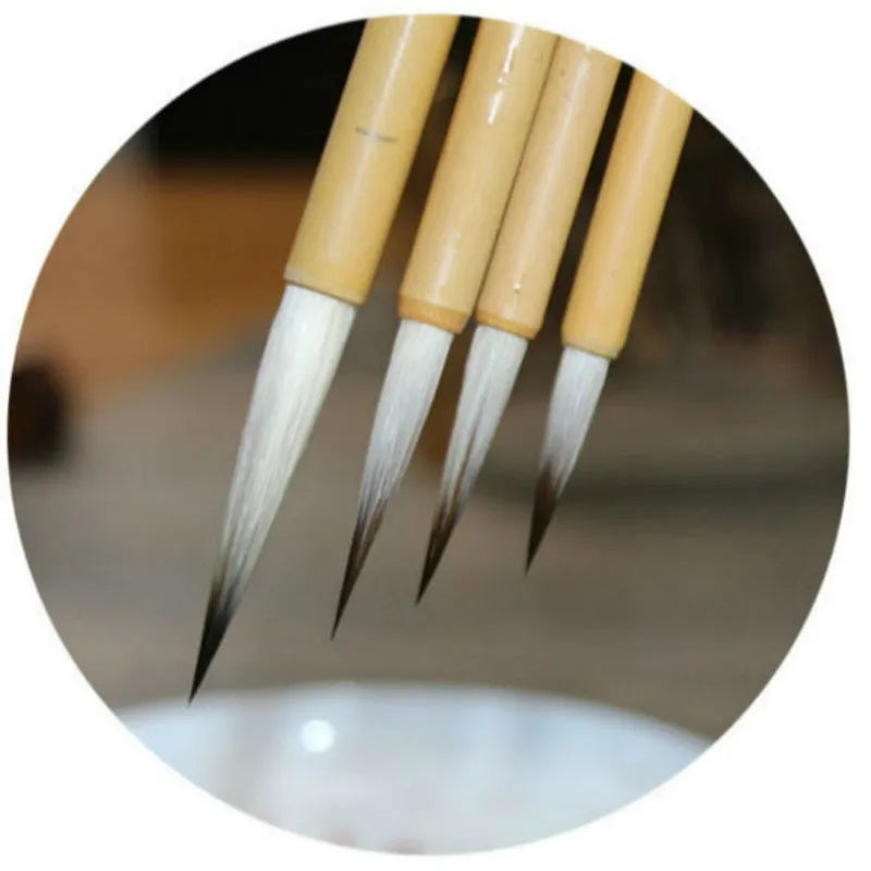 Four gold-coloured thin writing brushes with pine branch design, size 0, on a flat surface.