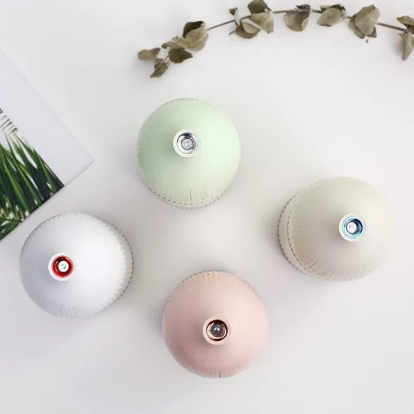 White USB-powered ultrasonic aromatherapy diffuser and humidifier with LED light on a wooden surface.