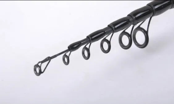 Telescopic carbon fishing rod with matte coating and reel seat on a lakeside bank