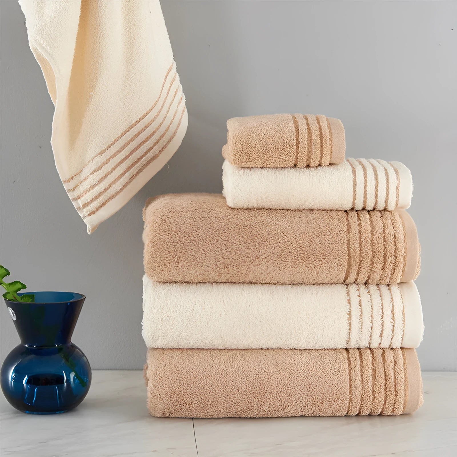Beige and brown cotton towel set showing bath towel, hand towel, and face cloth sizes