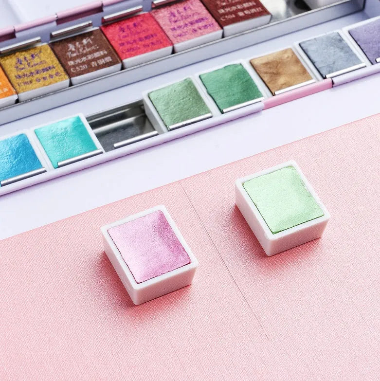 Open palette showing 12 solid pearl watercolour pans in a plastic case with a clear lid.