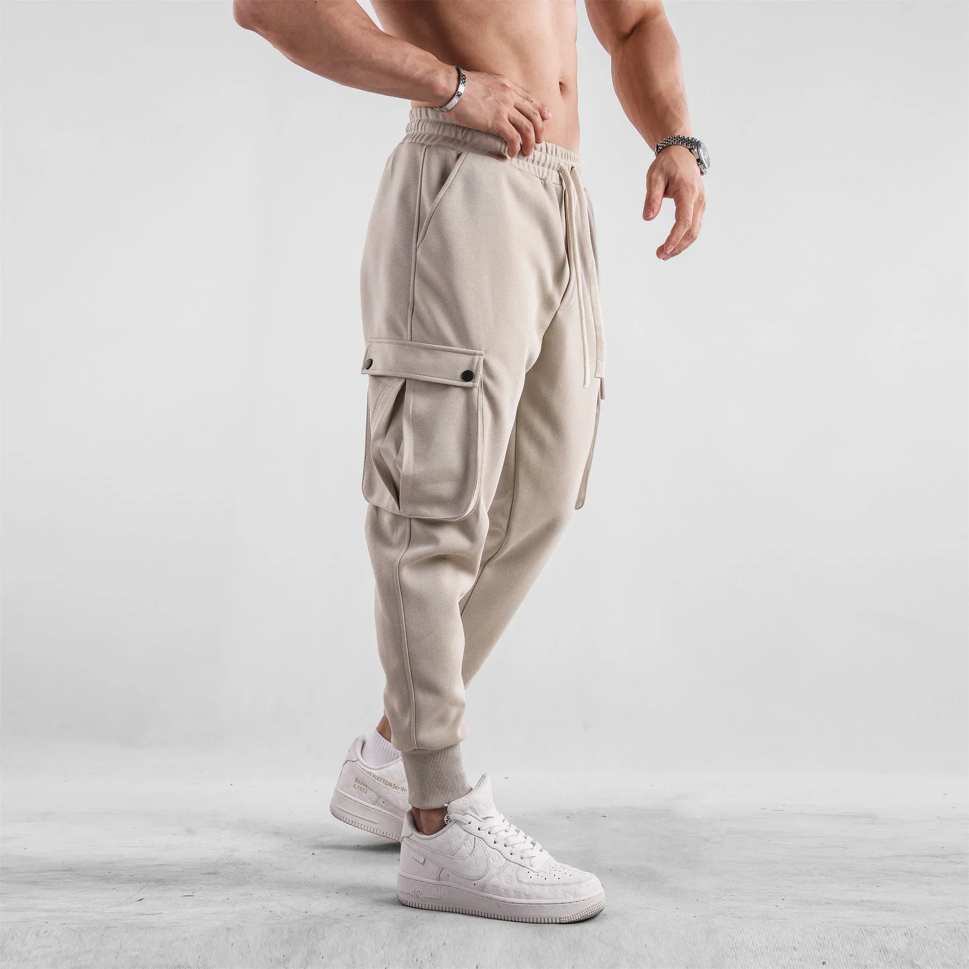 Men's loose-fit cotton sports trousers in apricot colour with ankle ties and multiple pockets, laid flat.