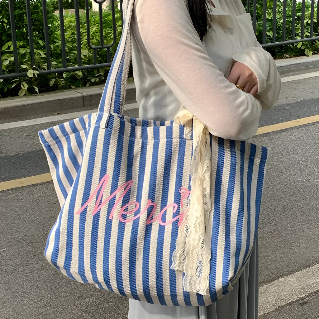 Blue striped letters printed on a pink, blue and white striped cotton canvas bag.