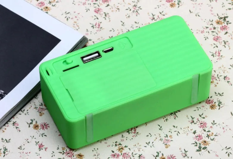 Small cube-shaped wireless Bluetooth speaker in multiple colours showing its compact, waterproof design