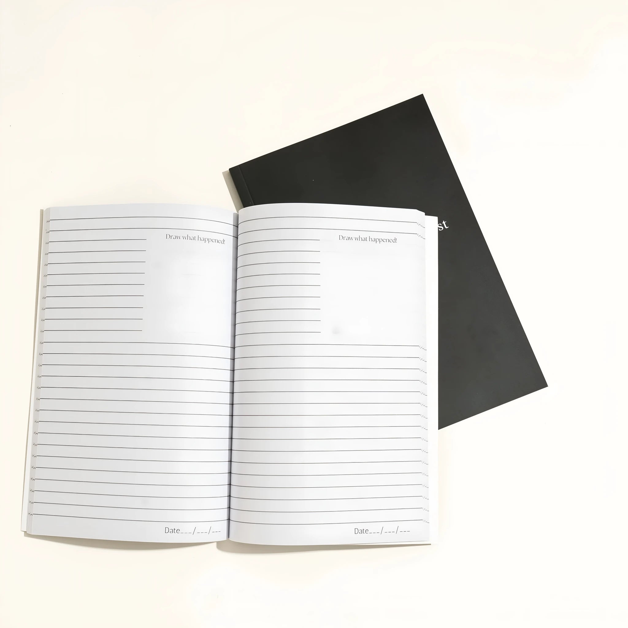 Black hardcover dream journal notebook with ruled pages open on a table.