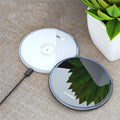 Black aluminium alloy 15W Qi wireless charging pad on a table with LED light.