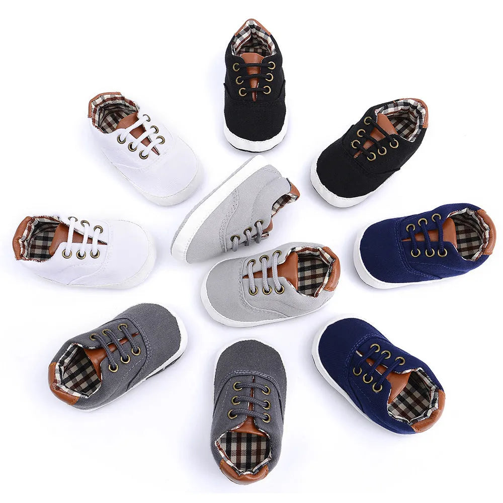 Solid colour baby canvas shoes with a front strap, shown in light grey on a white background.
