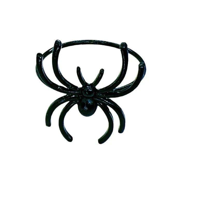 Six black alloy spider-shaped napkin rings for Halloween table decoration on a dark tablecloth.