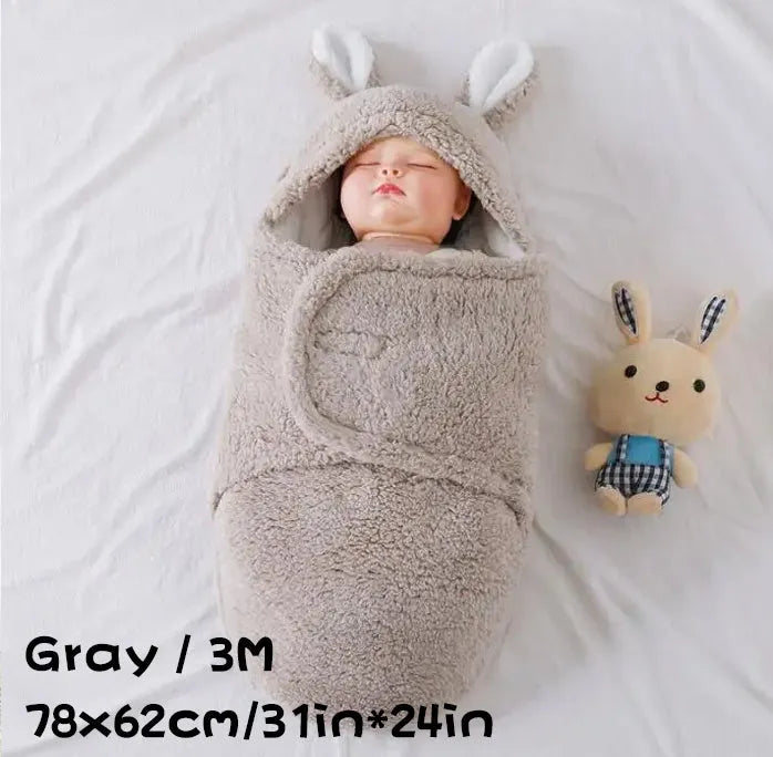 Baby wearing a grey adjustable fleece swaddle sleep sack with velcro wings