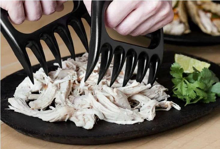 Two black bear claw meat shredders for barbecue preparation on kitchen counter