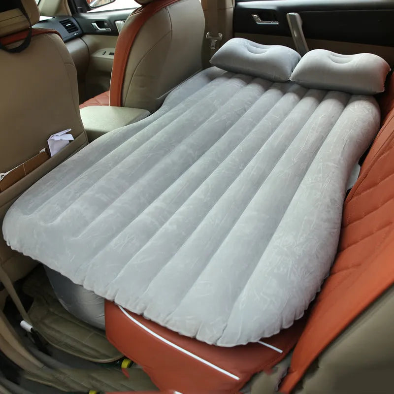 Inflatable car bed with flocked surface and pillows, set up in the back of a five-seater vehicle.