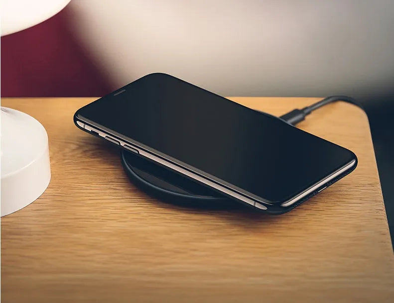 Black glass disc wireless charger with LED indicator light on smooth surface