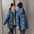 Green loose-fit women's hooded winter jacket with long sleeves on a hanger