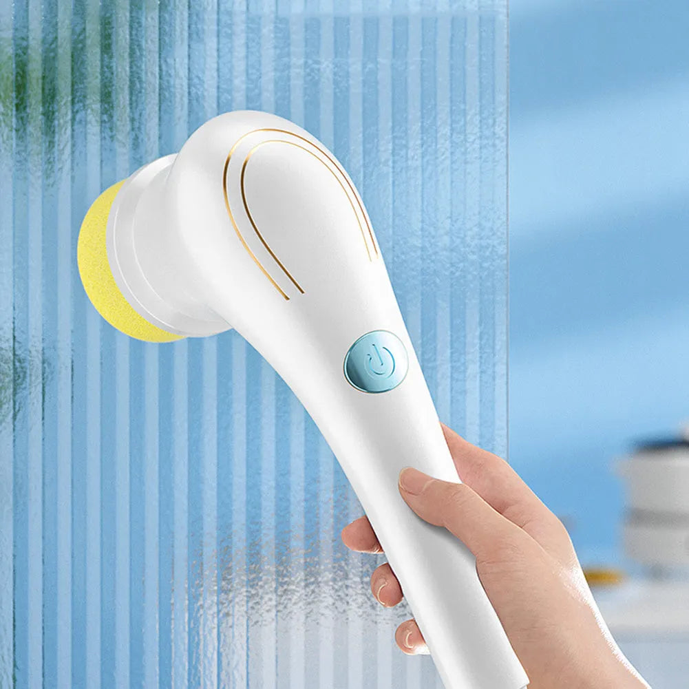 White cordless electric handheld scrubber with five attached brush heads on a table next to a USB charging cable.