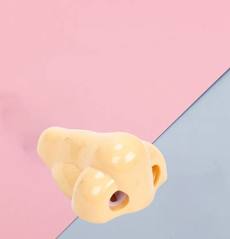 Flesh-coloured plastic manual pencil sharpener with a geometry shape, shown next to a pencil for scale.