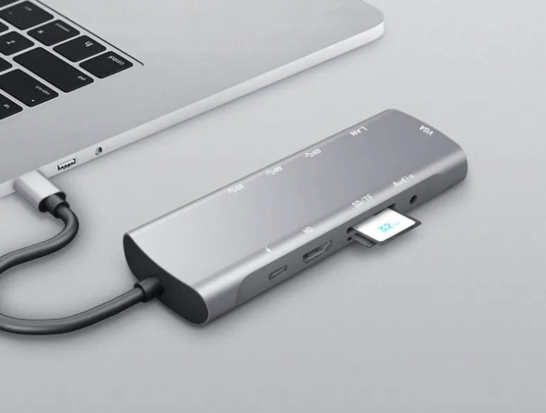 Grey aluminium USB-C docking station with multiple ports including HDMI, VGA, and USB, showing its 140mm attached cable.