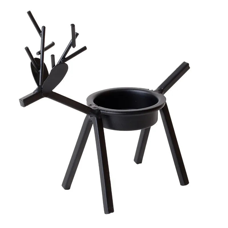 Black iron Christmas deer candlestick holder with elk silhouette on a table.
