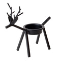 Black iron Christmas deer candlestick holder with elk silhouette on a table.