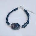 Dark obsidian cat climbing bracelet with carved feline sculpture along natural stone band