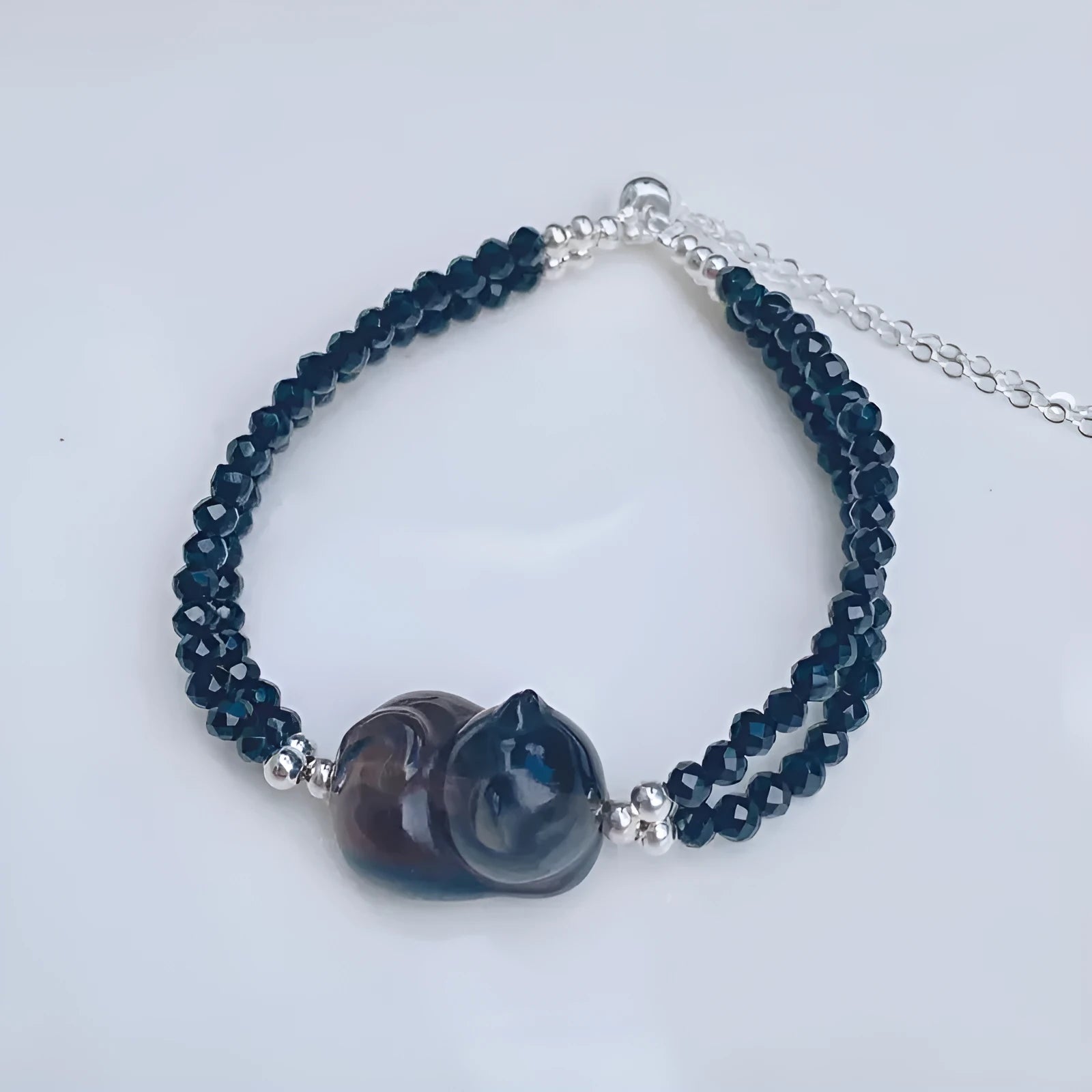 Dark obsidian cat climbing bracelet with carved feline sculpture along natural stone band